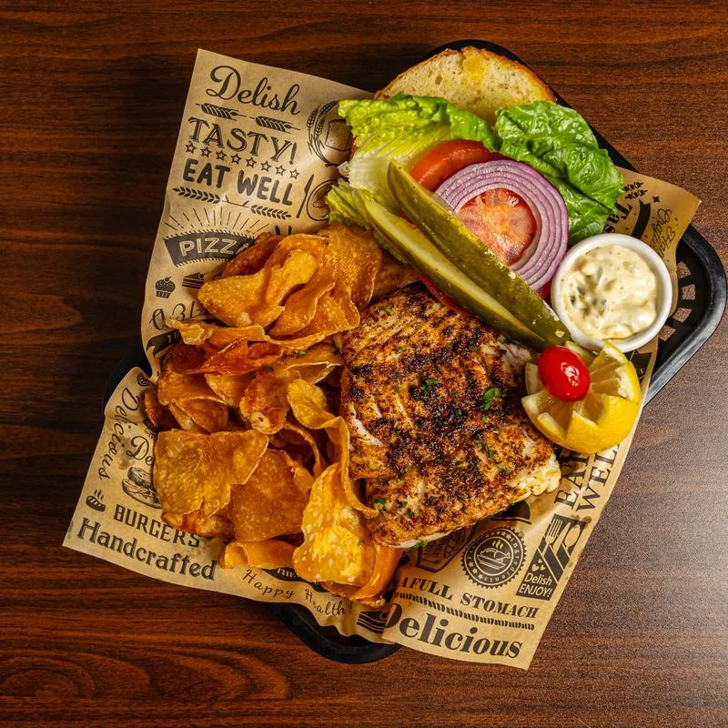 Blackened grouper sandwich with fries and pickle