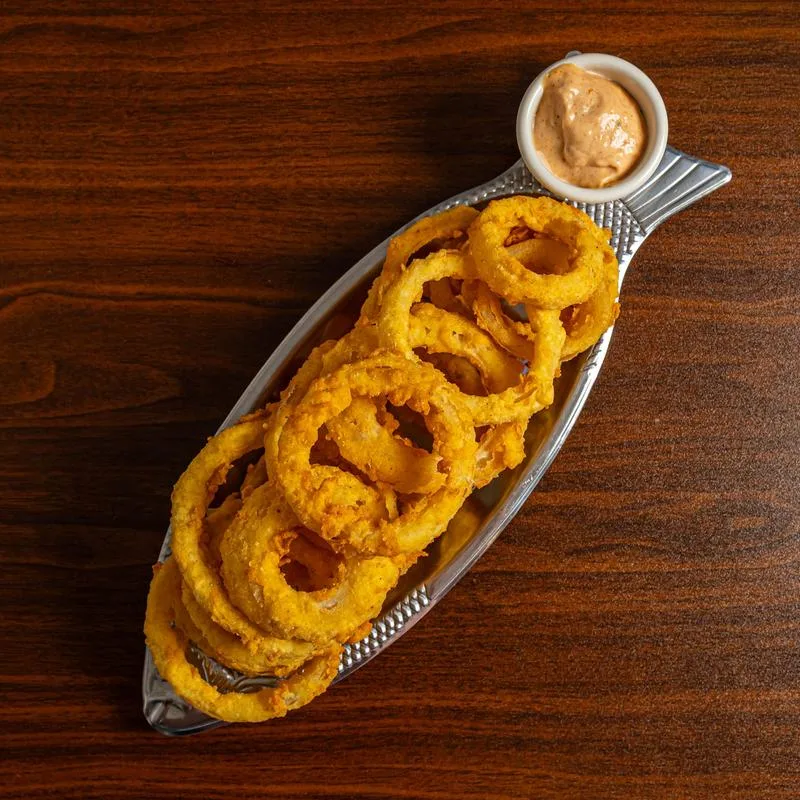 Onion rings served on a fish-shaped tray with dipping sauce